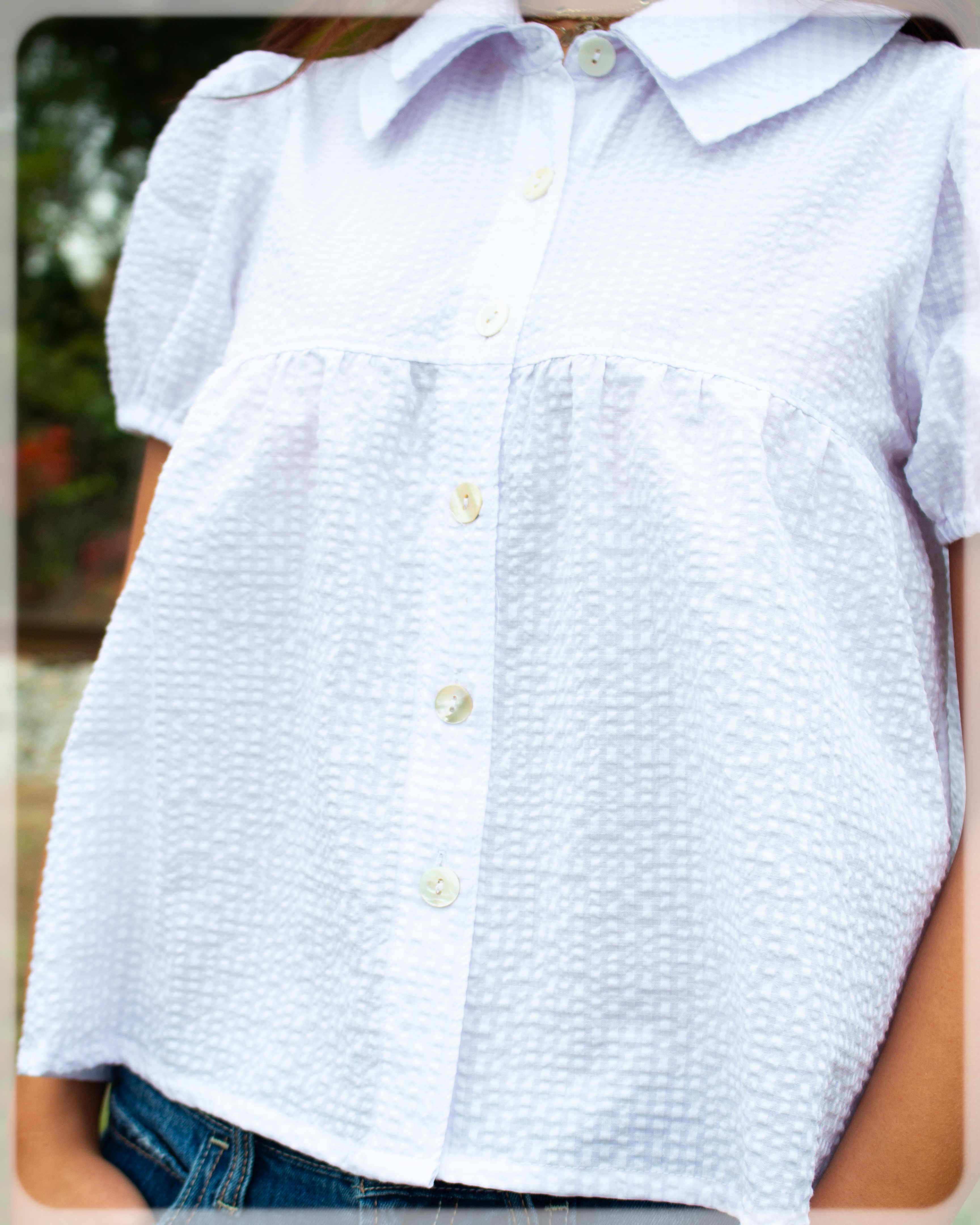 White button up collared textured shirt worn by a person with a blurred background