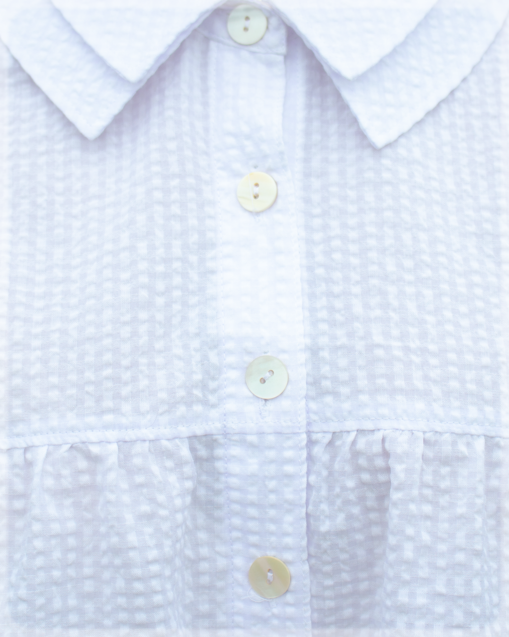 Close-up of a White textured seersucker checkered shirt blouse with buttons