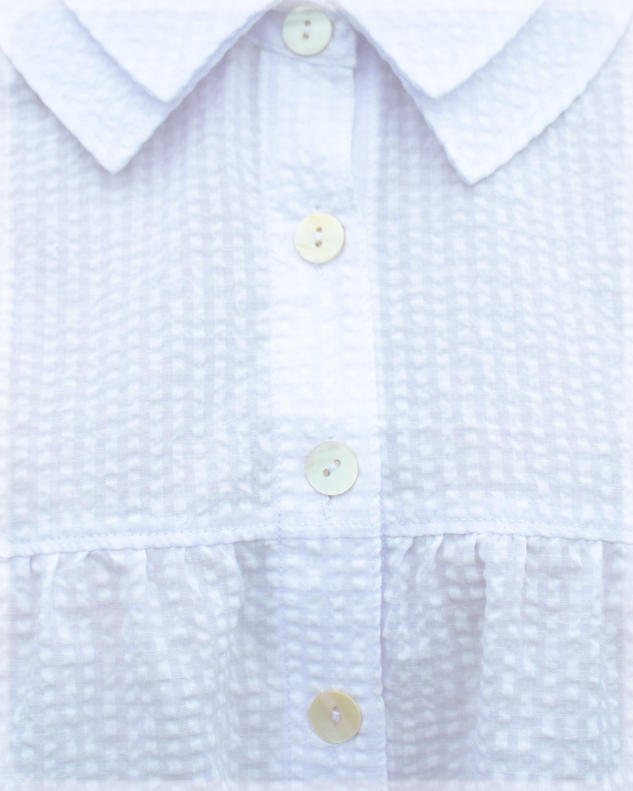 Close-up of a White textured seersucker checkered shirt blouse with buttons