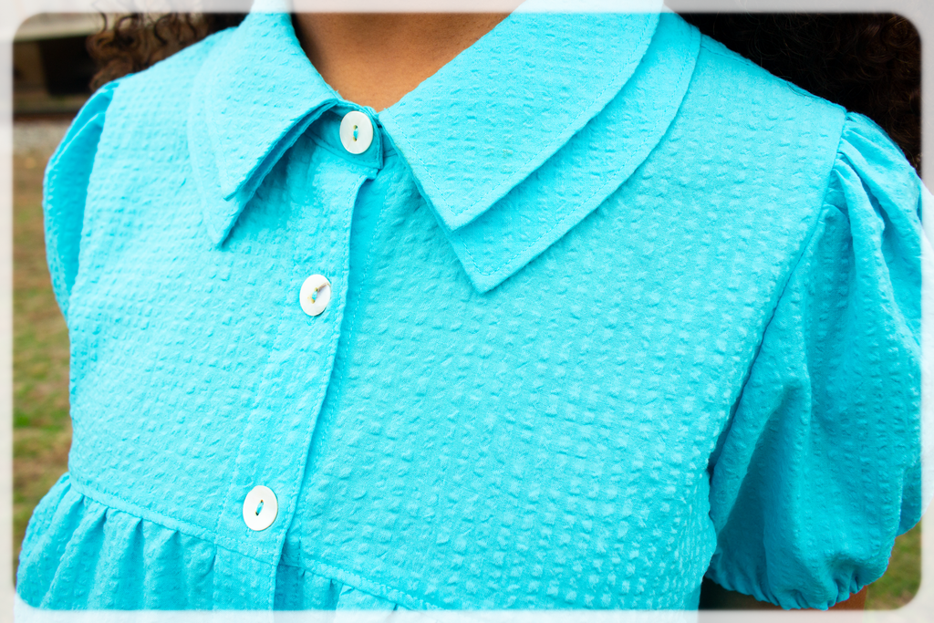 Close-up of a Bright Cerulean blue turquoise dress with a collar and buttons.