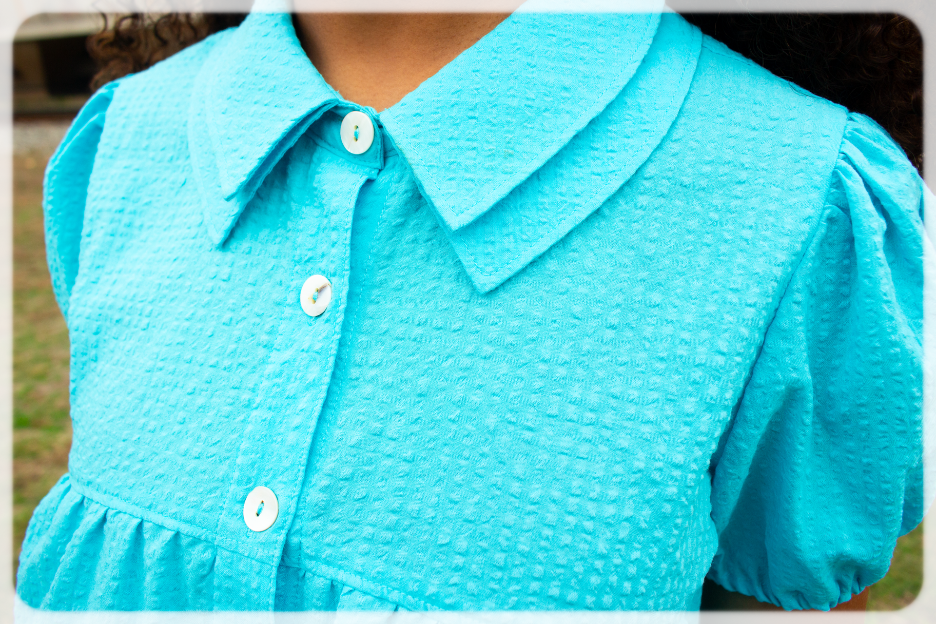 Close-up of a Bright Cerulean blue turquoise dress with a collar and buttons.