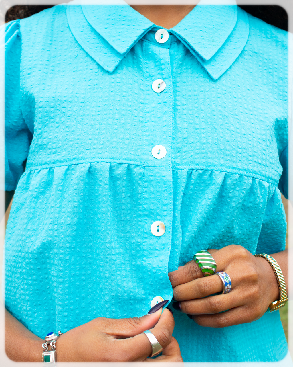 Close-up of a person wearing a Bright Cerulean blue turquoise shirt with buttons.